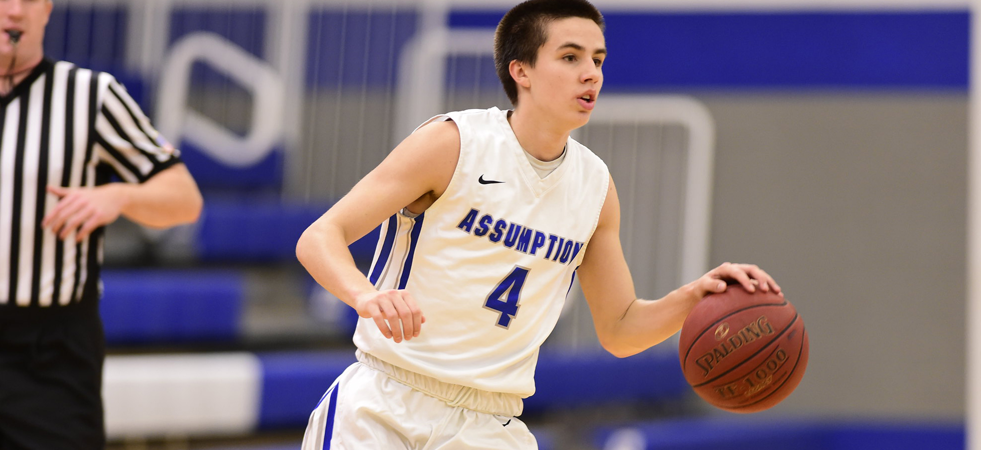 Assumption basketball player dribbling up the court