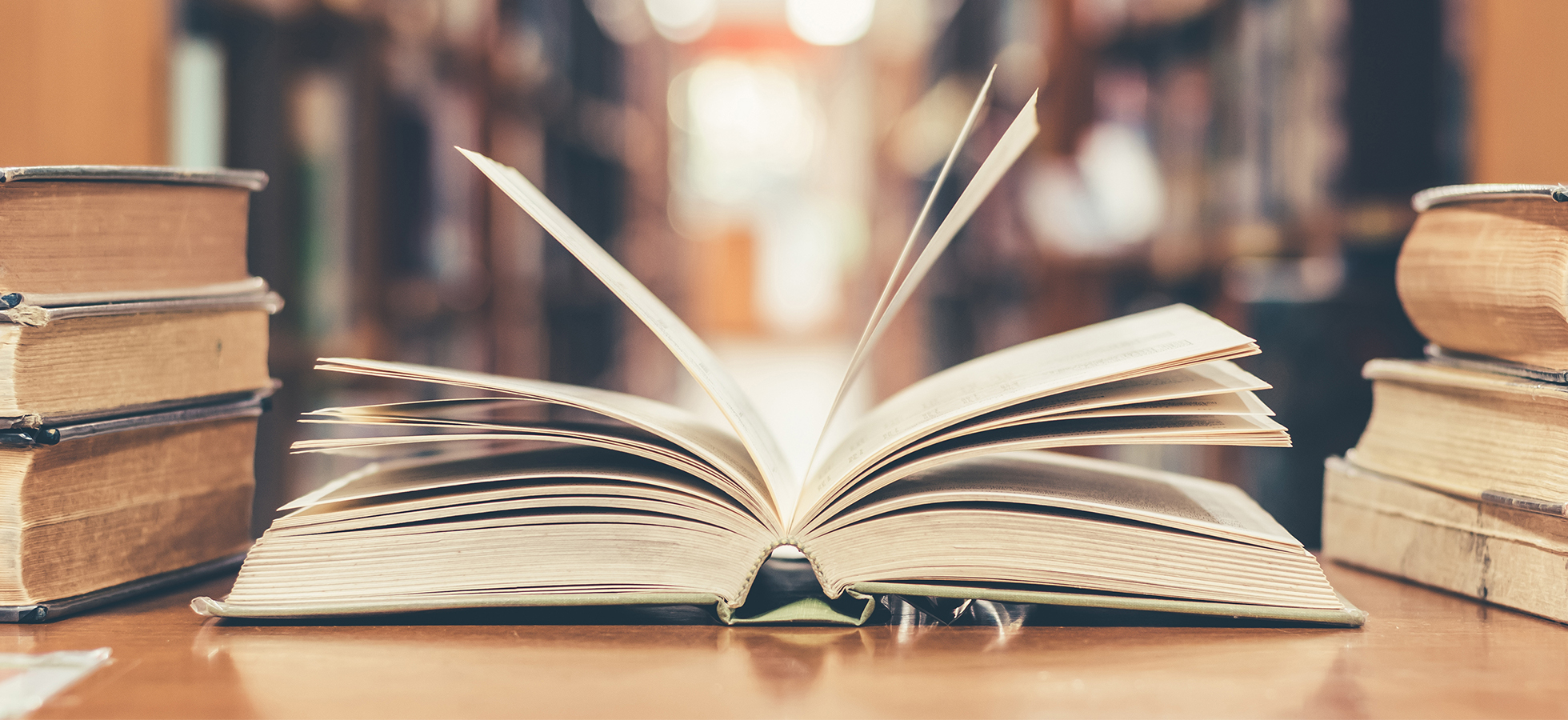 Photo of an open book in a library to promote the Inaugural Michael True Poetry Reading at Assumption College