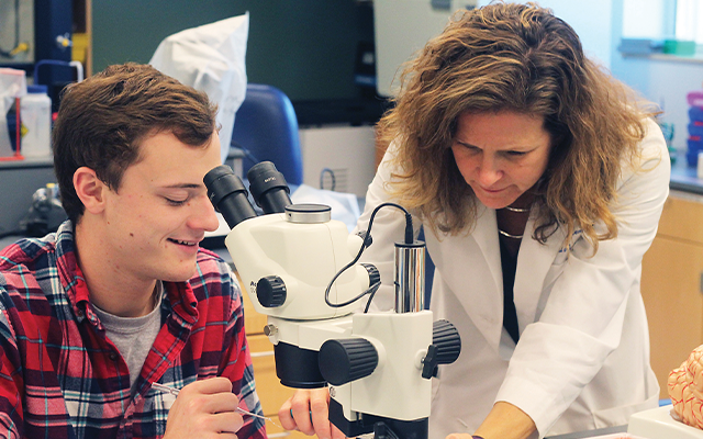 Student and professor working with a microscope