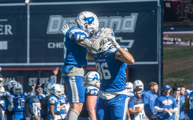 Two football players celebrating on the field after a score.