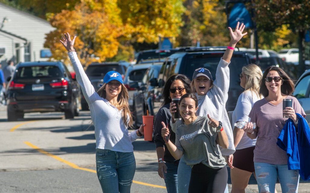 Group of students smiling with their hands up cheering.