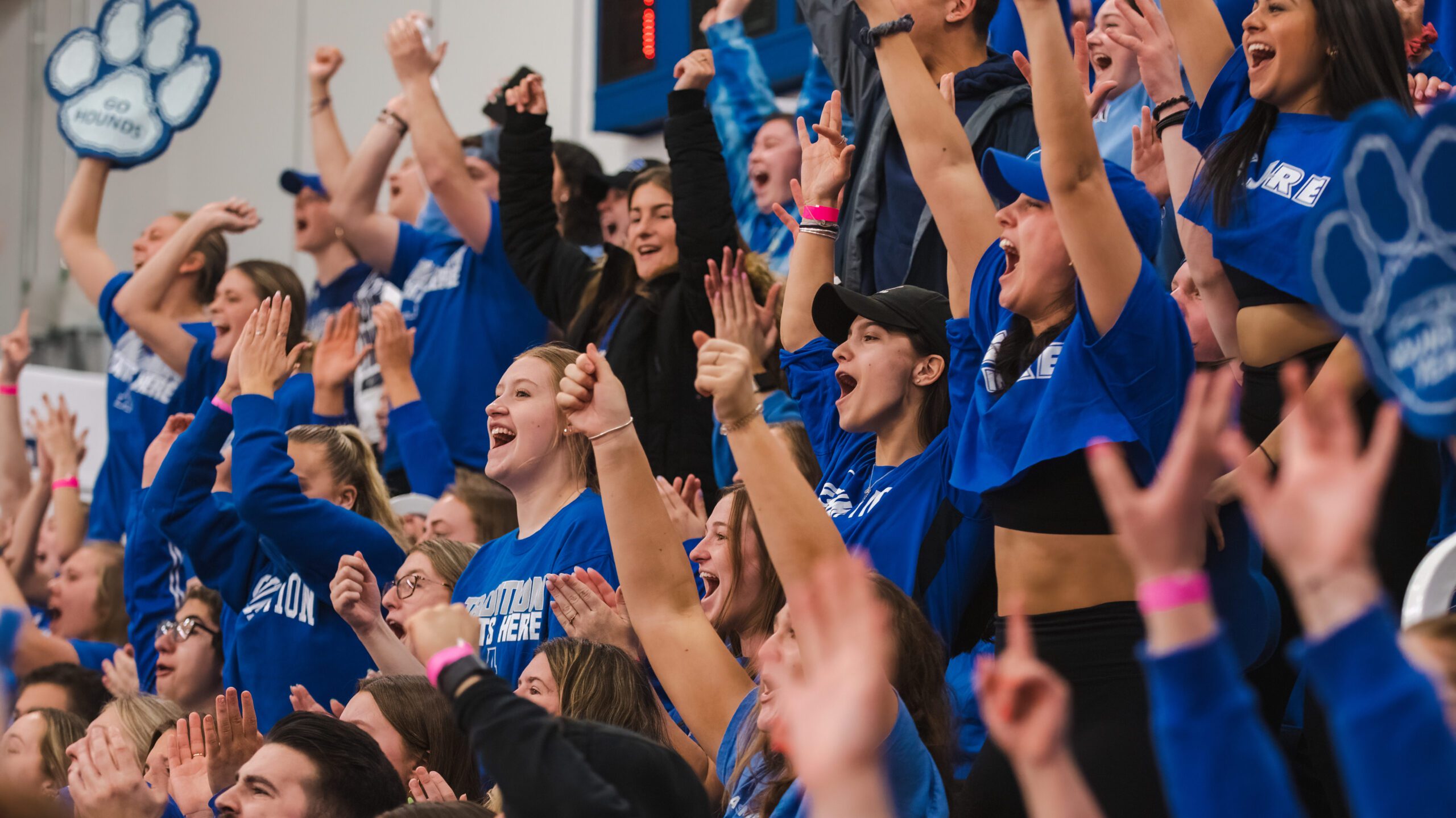 Assumption Greyhounds fans wearing blue cheer during a basketball game in Laska Gymnasium