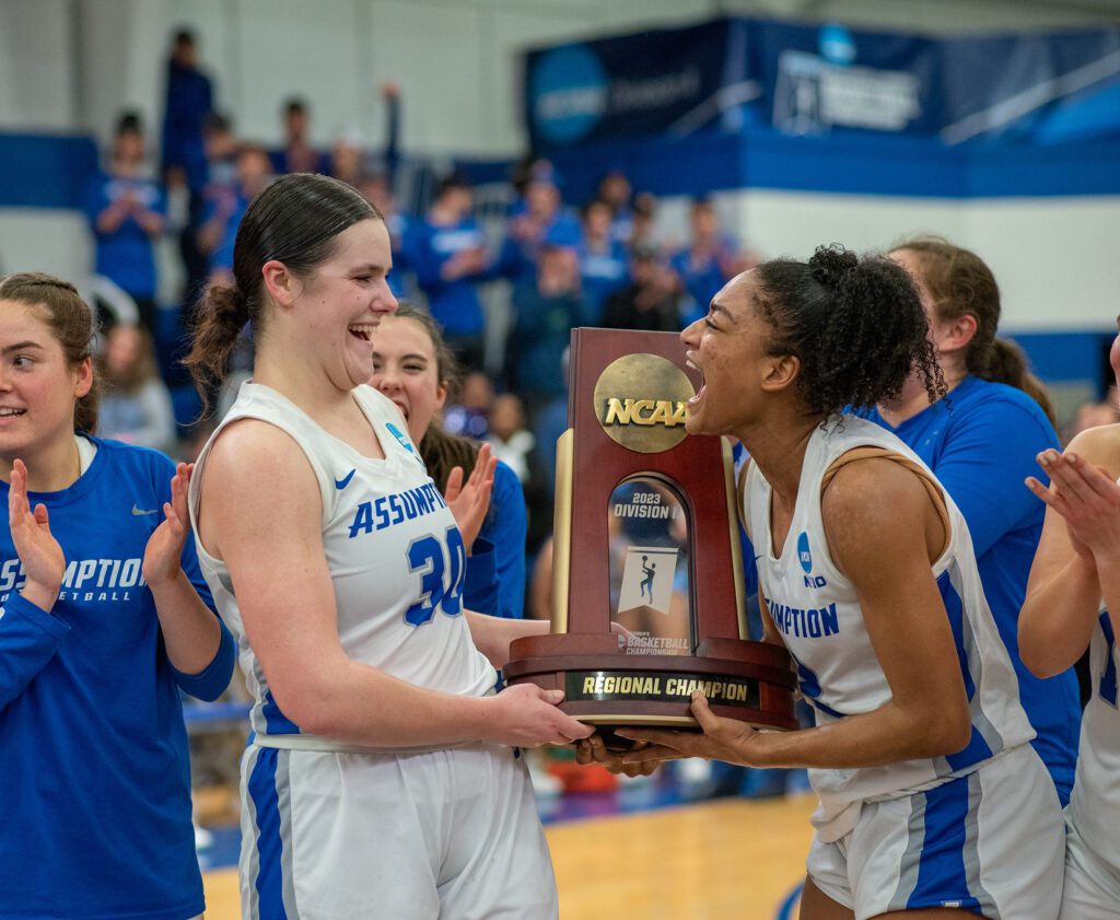 Assumption University women's basketball players holding an NCAA trophy after winning the 2023 East Regional Tournament