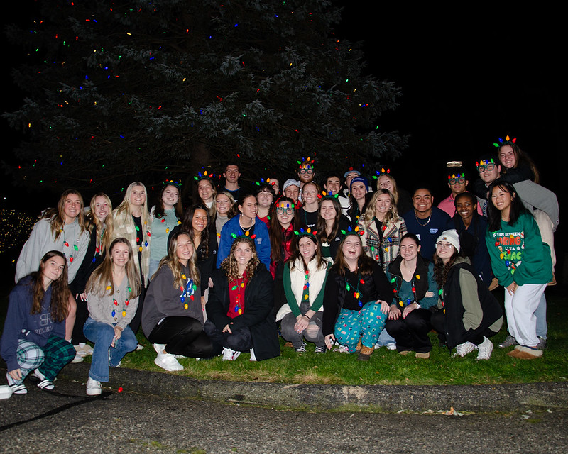 Assumption students wearing Christmas outfits under Assumption's Christmas tree