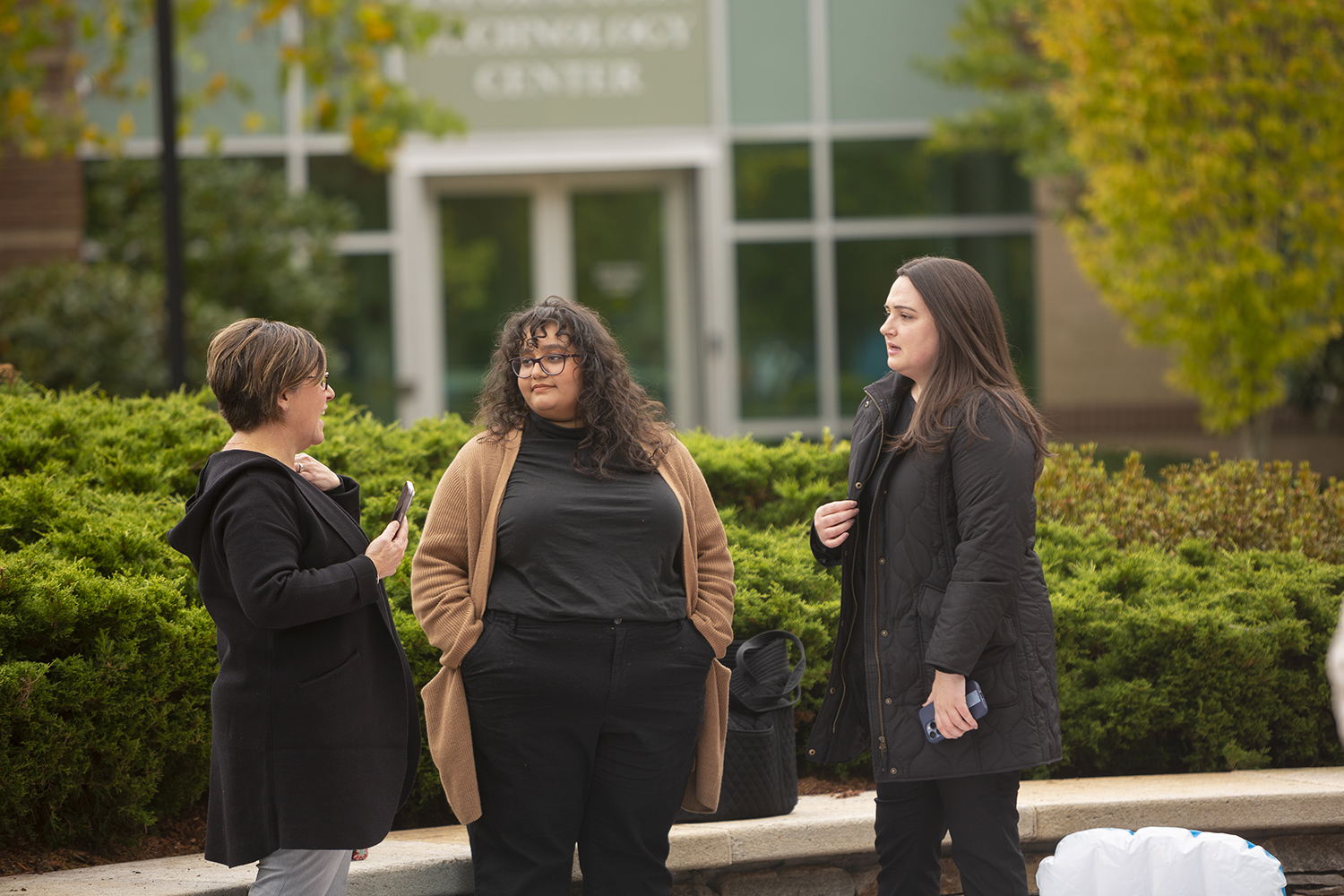 Three females standing in a group outside.