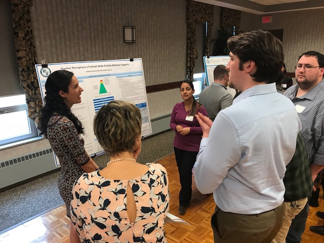 graduate students viewing a poster presentation