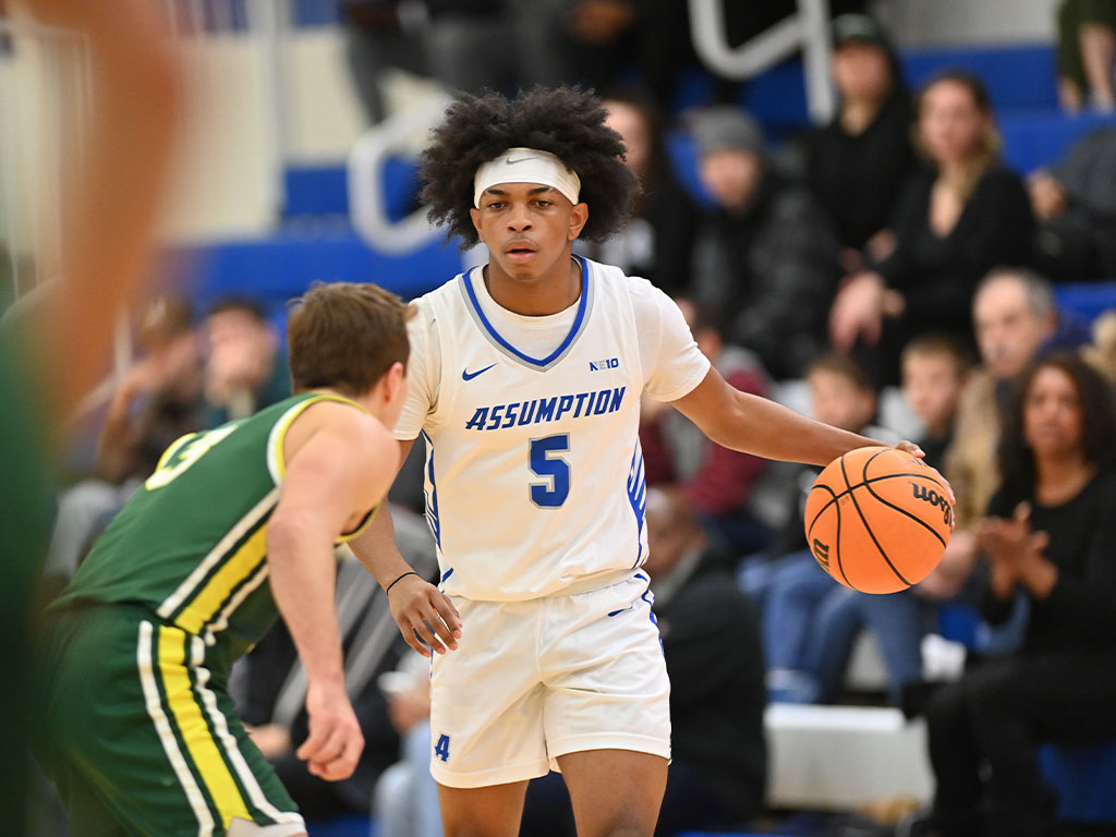 Assumption basketball player dribbles the ball